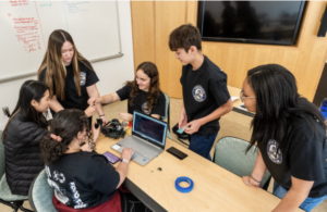 Ayla Zook (fourth from left, sitting) works with her teammates at UMW’s Dahlgren Campus during the third annual High School Innovation Challenge @ Dahlgren. The team, from King George County High School, took top prize, claiming $3,500 for STEM learning at their school. Photo by Dave Ellis.